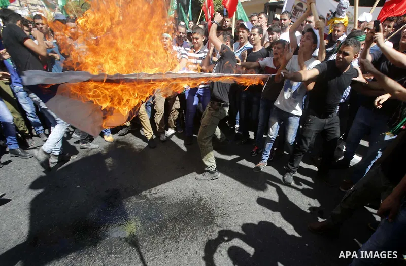 Palestinian protesters burn an Israeli flag during a demonstration in defence of the Al-Aqsa mosque, Islam s third holiest site, located in Jerusalem's old city, after the weekly Friday prayers, in the occupied West Bank...
