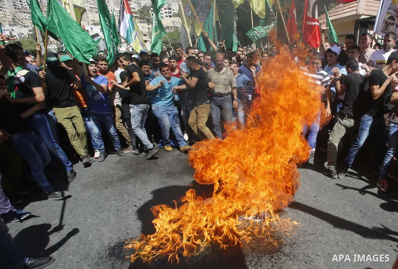 Palestinian protesters burn an Israeli flag during a demonstration in defence of the Al-Aqsa mosque, Islam s third holiest site, located in Jerusalem's old city, after the weekly Friday prayers, in the occupied West Bank...