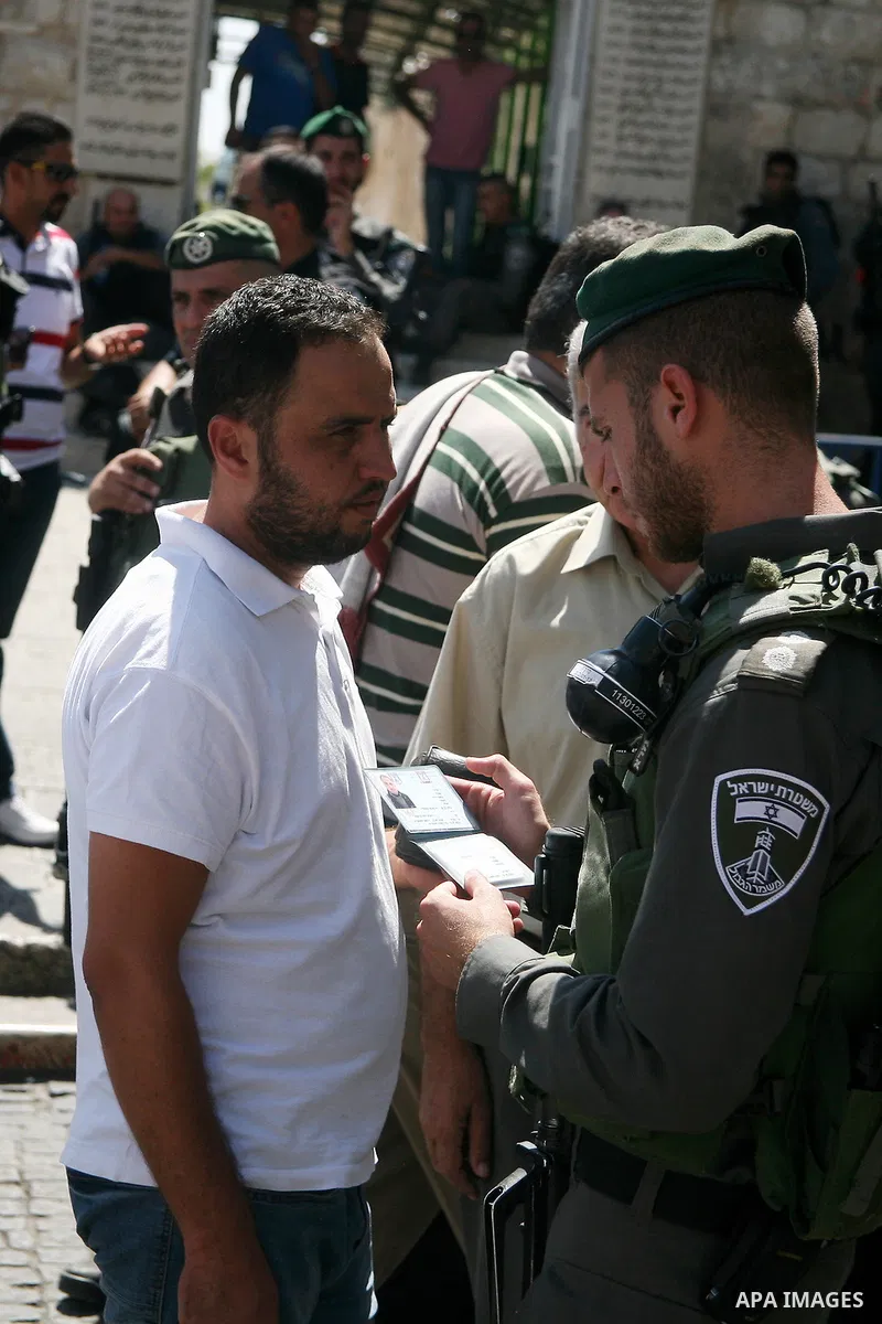 An Israeli policeman checks the ID of a Palestinian Muslim worshiper before entering the Al-Aqsa mosque to perform he traditional Friday prayers, as Israeli police blocks the access to Al-Aqsa Mosque, outside the Old Cit...