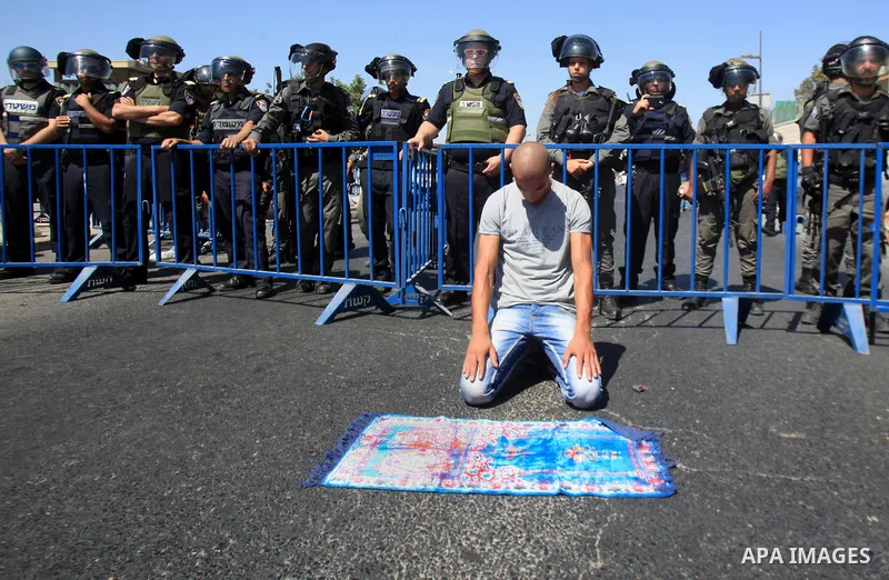 A Palestinian Muslim worshipper, under the age of 40 years old, performs the traditional Friday prayers on a street as Israeli police blocks the access to Al-Aqsa Mosque, outside the Old City walls in East Jerusalem on S...