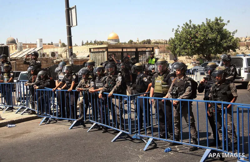 Israeli policemen stand guard as Palestinian Muslim worshippers, under the age of 40 years old, perform the traditional Friday prayers on a street, outside the Old City walls in East Jerusalem on September 18, 2015. Isra...