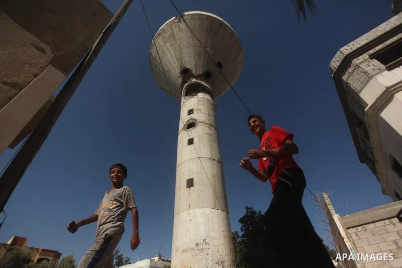 Palestinian boys look at a water tower targeted by an Israeli air strike overnight in the northern Gaza strip of Beit Hanun on September 19, 2015. Two rockets were fired into southern Israel by Palestinian militants in G...