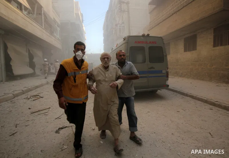 A civil defence worker helps a Syrian man following an air strike by government forces on the al-Mowasalat neighbourhood of the northern Syrian city of Aleppo on September 20, 2015. Photo by Ameer al-Halbi