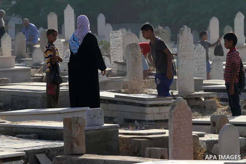 Palestinians pray over the graves of relatives in a cemetery, on the Muslim holiday of Eid al-Adha or or the feast of sacrifice, in Gaza city on September 24, 2015. Muslims across the world are celebrating the annual fes...