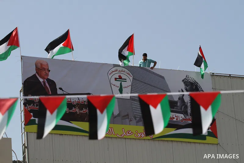 A Palestinian man stands nexto to his national flags during an event to support Palestinian President Mahmoud Abbas in the West Bank city of Nablus on September 30, 2015. Abbas has circulated a hard-hitting critique of a...