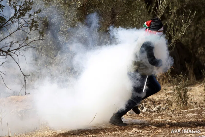 A Palestinian protester runs for cover from tear gas fired by Israeli security forces during clashes in Budrus village, west of Ramallah on October 2, 2015. Two Israeli settlers were shot and killed in a drive-by shootin...
