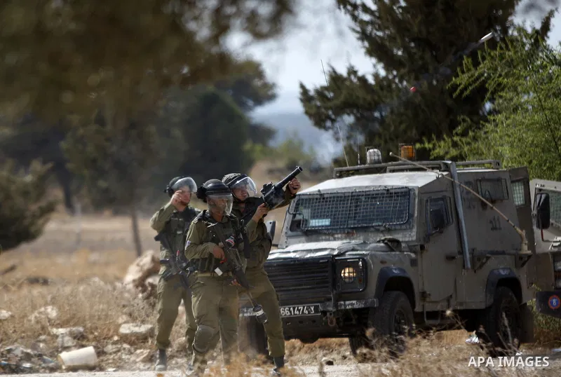 A member of Israeli security forces fires tear gas towards Palestinian protesters during clashes in Budrus village, west of Ramallah on October 2, 2015. Two Israeli settlers were shot and killed in a drive-by shooting be...