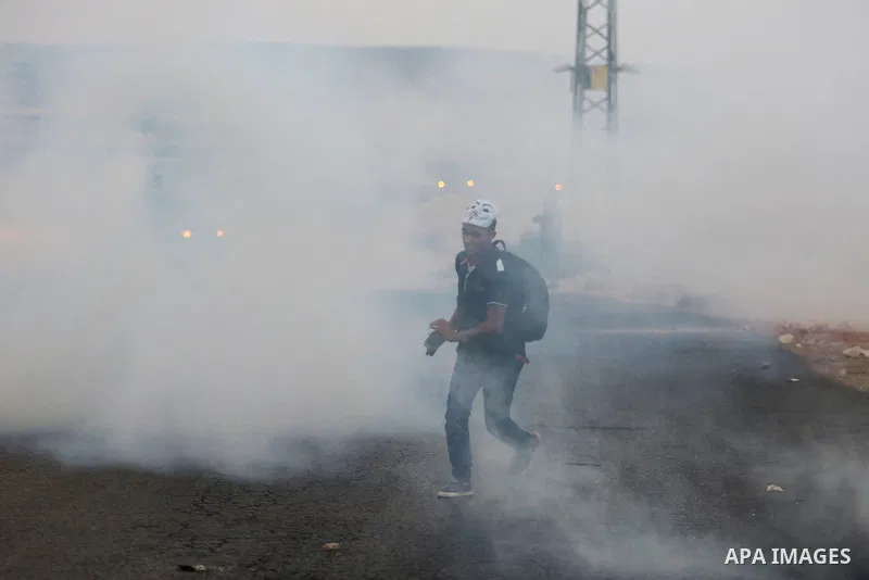 A Palestinian protester runs for cover from tear gas fired by Israeli soldiers during clashes close to the Jewish settlement of Bet El, in the West Bank city of Ramallah on October 4, 2015 after Israel barred Palestinian...