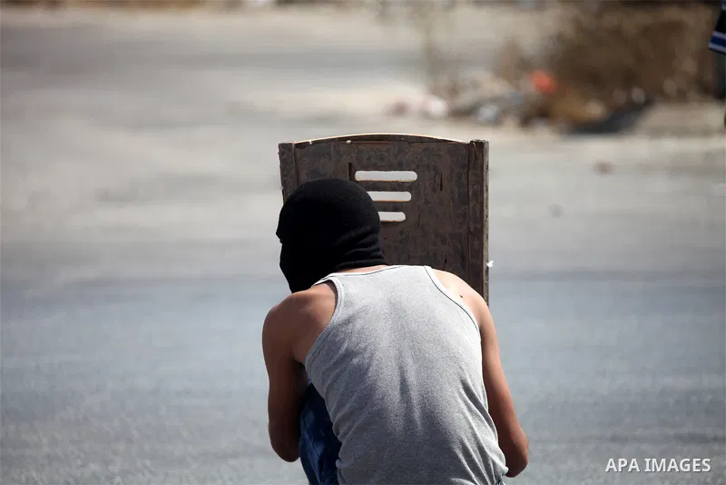 A Palestinian protester takes cover during clashes with Israeli troops near the Jewish settlement of Bet El, near the occupied West Bank city of Ramallah October 5, 2015. Violence intensified in Jerusalem and the West Ba...