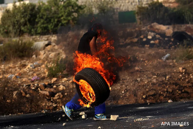 A Palestinian protester burn tires during clashes with Israeli troops near the Jewish settlement of Bet El, near the occupied West Bank city of Ramallah October 5, 2015. Violence intensified in Jerusalem and the West Ban...