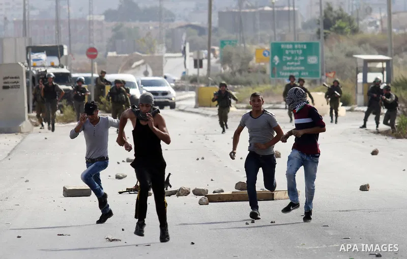 Israeli security forces run after Palestinian protesters during clashes at the Howara checkpoint near the West Bank city of Nablus, October 9, 2015. Tension and protests rose after an Israeli man on 09 October stabbed fo...