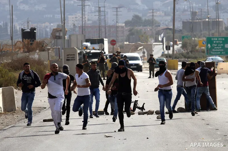 Israeli security forces run after Palestinian protesters during clashes at the Howara checkpoint near the West Bank city of Nablus, October 9, 2015. Tension and protests rose after an Israeli man on 09 October stabbed fo...