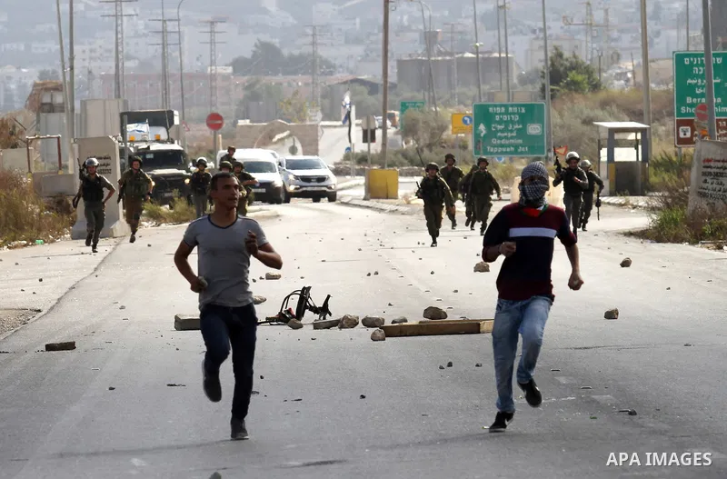 Israeli security forces run after Palestinian protesters during clashes at the Howara checkpoint near the West Bank city of Nablus, October 9, 2015. Tension and protests rose after an Israeli man on 09 October stabbed fo...