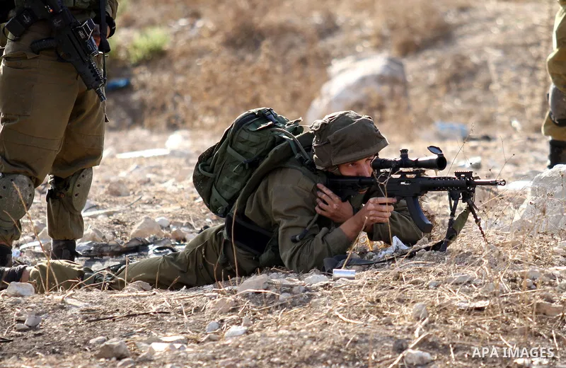 A member of Israeli security forces aims at Palestinian protesters during clashes at the Howara checkpoint near the West Bank city of Nablus, October 9, 2015. Tension and protests rose after an Israeli man on 09 October...