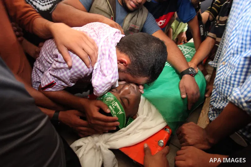 Palestinian militants of the Ezzedine al-Qassam Brigades, Hamas' armed wing, carry the body of Palestinian protester 22-year-old Jihad al-Obeid, who died in clashes with Israeli security forces near the border, during hi...