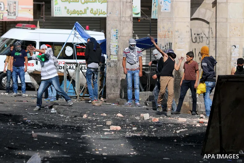 Palestinian protesters throw stones during clashes with Israeli troops in Hebron, West Bank, Saturday, Oct. 10, 2015. Fifteen Palestinians have been killed by Israeli forces and around 1,000 injured with live and rubber-...