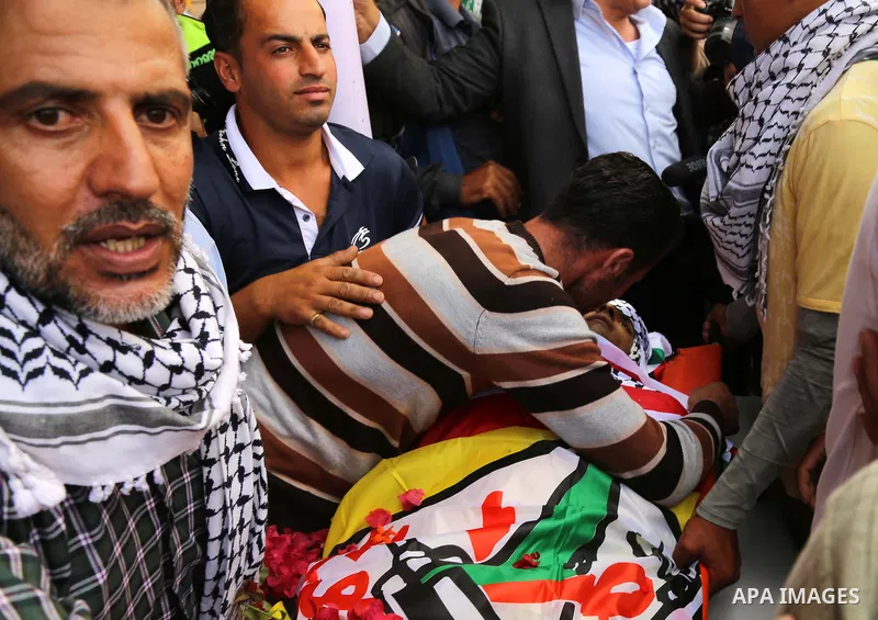 Relatives of Palestinian Amjad Al-joundi, mourn around his body during his funeral, in the Yatta, south of the West Bank city of Hebron October 10, 2015. Fifteen Palestinians have been killed by Israeli forces and around...