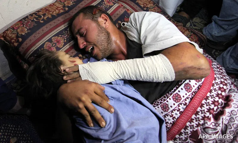 Palestinian father Yehya Hasan mourns while holding the body of his daughter, Rahaf, during a funeral for the toddler and her pregnant mother on October 11, 2015, at the al-Nusairat refugee camp, in central Gaza Strip. A...