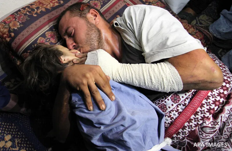 Palestinian father Yehya Hasan mourns while holding the body of his daughter, Rahaf, during a funeral for the toddler and her pregnant mother on October 11, 2015, at the al-Nusairat refugee camp, in central Gaza Strip. A...