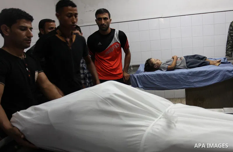 People stand around the body of a Palestinian woman who was killed after her house was brought down by an Israeli air strike in Gaza early on October 11, 2015. An Israeli air strike on a Hamas target in the Gaza Strip on...