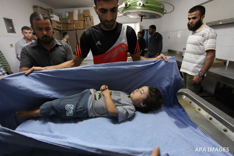 People stand around the body of a three-year-old Palestinian girl who was killed after her house was brought down by an Israeli air strike in Gaza early on October 11, 2015. An Israeli air strike on a Hamas target in the...