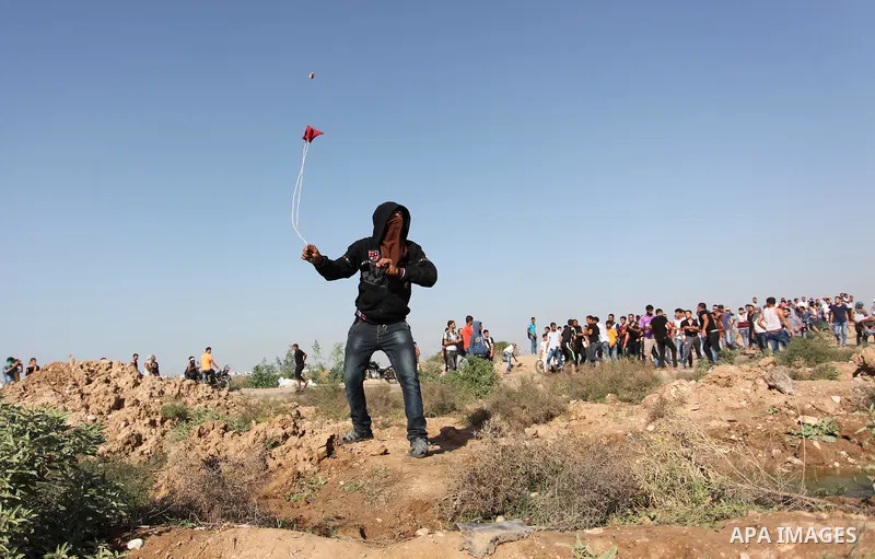 A Palestinian protester uses a sling shot to throw stones towards Israeli security forces during clashes near the border fence between Israel and the Gaza Strip on October 11, 2015, east of Gaza City. An Israeli air stri...