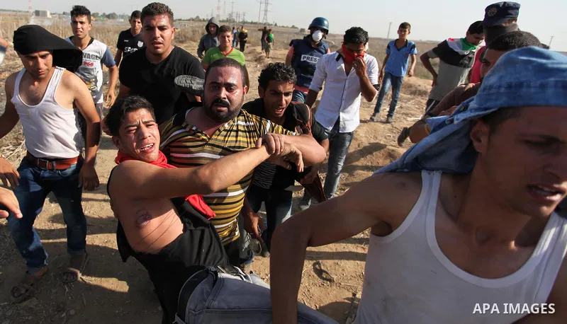 Palestinian protestors carry an injured comrade during clashes with Israeli security forces near the border fence between Israel and the Gaza Strip on October 11, 2015, east of Gaza City. An Israeli air strike in Gaza ki...