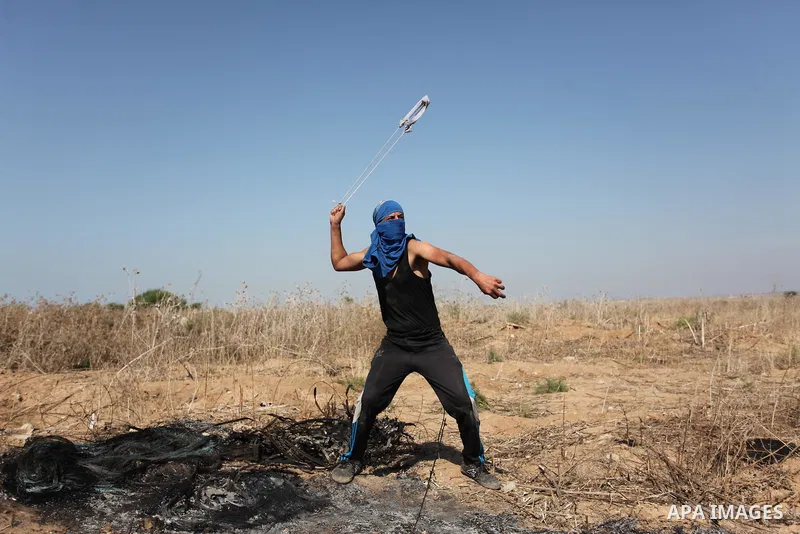 A Palestinian protester uses a sling shot to throw stones towards Israeli security forces during clashes near the border fence between Israel and the Gaza Strip on October 11, 2015, east of Gaza City. An Israeli air stri...