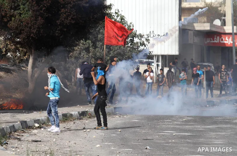 Palestinian protesters for cover from tear gas fired by Israeli security forces during clashes at the Hawara checkpoint, south of the West Bank city of Nablus, on October 13, 2015. A wave of stabbings that hit Israel, Je...