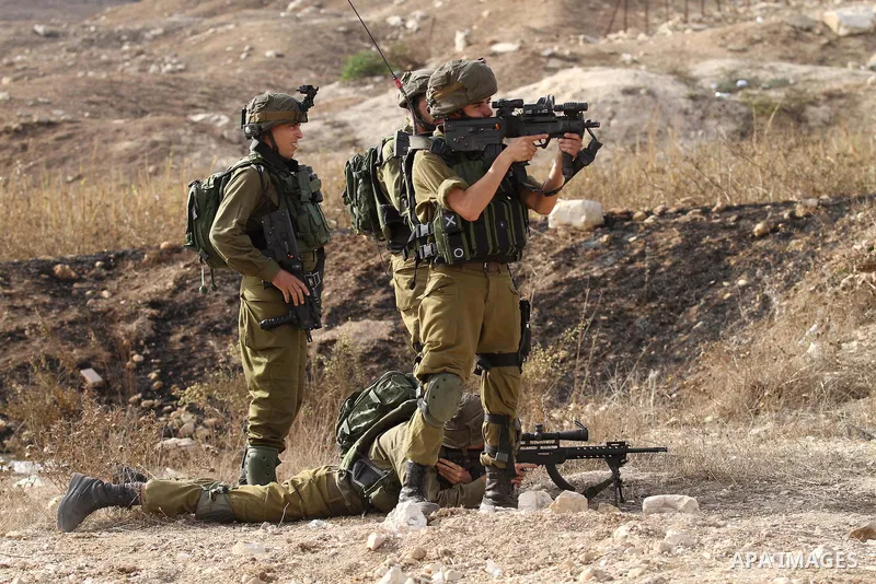 An Israeli soldier aims at Palestinian protesters during clashes at the Hawara checkpoint, south of the West Bank city of Nablus, on October 13, 2015. A wave of stabbings that hit Israel, Jerusalem and the West Bank this...