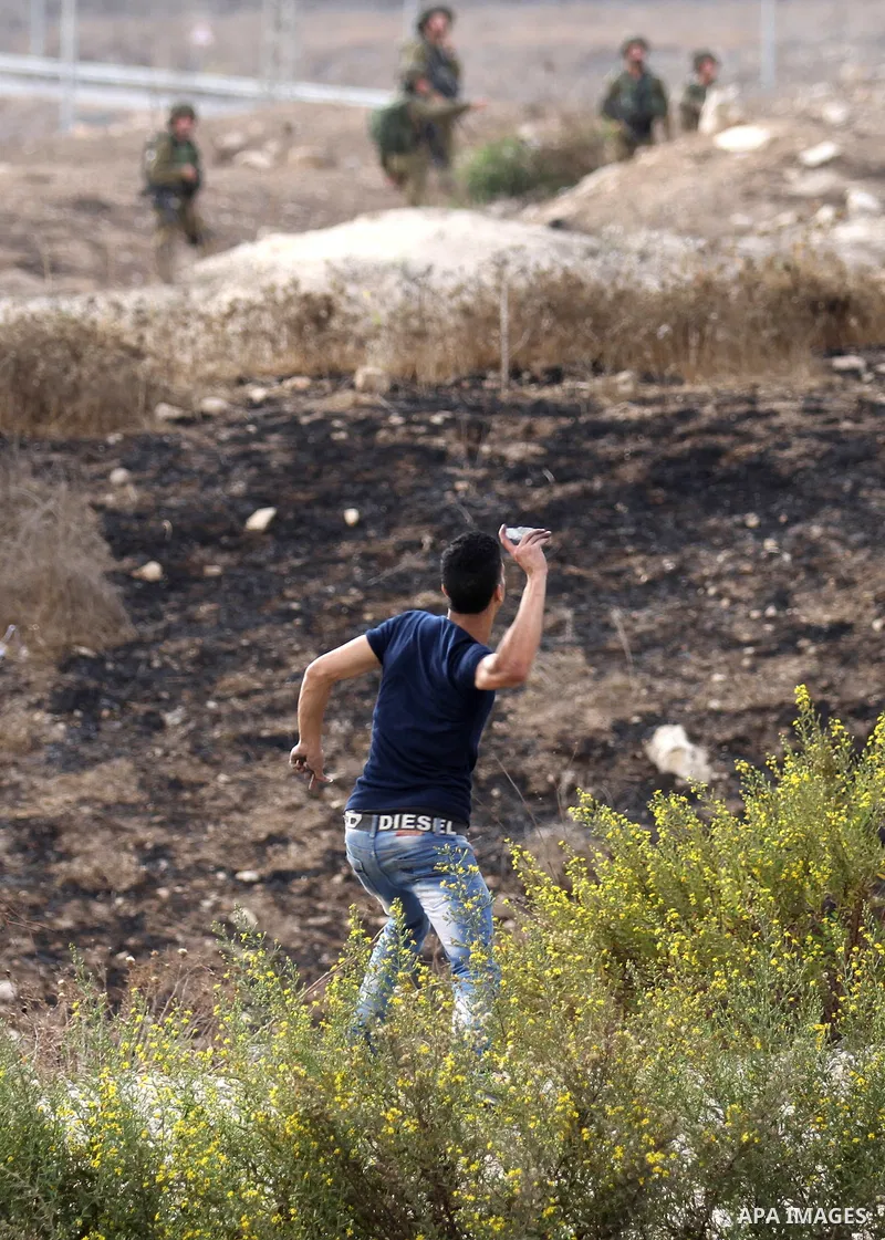 A Palestinian protester throws stones at Israeli security forces during clashes at the Hawara checkpoint, south of the West Bank city of Nablus, on October 13, 2015. A wave of stabbings that hit Israel, Jerusalem and the...