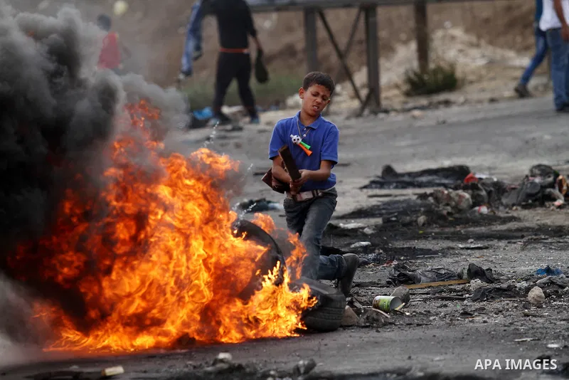 A Palestinian boy burns tires during clashes with Israeli security forces at the Hawara checkpoint, south of the West Bank city of Nablus, on October 13, 2015. A wave of stabbings that hit Israel, Jerusalem and the West...