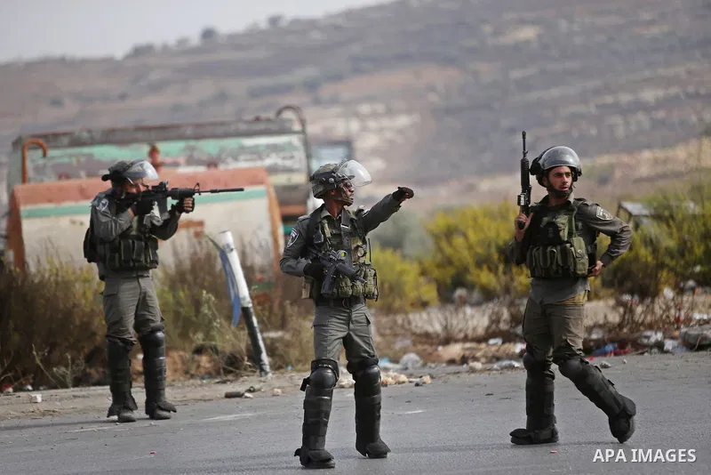 An Israeli soldier aims at Palestinian protester during clashes near the Jewish settlement of Bet El, near the West Bank city of Ramallah, on October 13, 2015. A wave of stabbings that hit Israel, Jerusalem and the West...