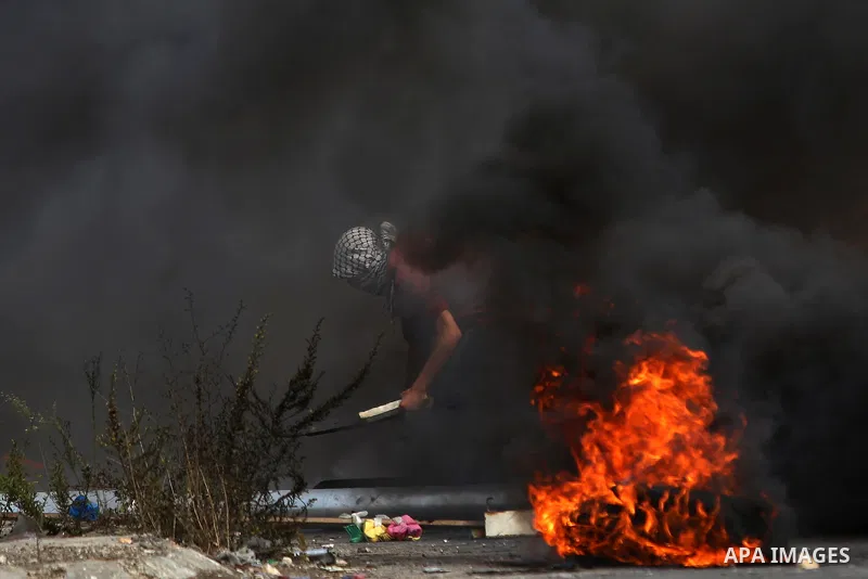 A Palestinian protester burns tires during clashes with Israeli security forces near the Jewish settlement of Bet El, near the West Bank city of Ramallah, on October 13, 2015. A wave of stabbings that hit Israel, Jerusal...