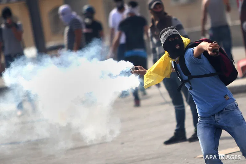 A Palestinian protester throws back a tear gas canister during clashes with Israeli security forces near the Jewish settlement of Bet El, near the West Bank city of Ramallah, on October 13, 2015. A wave of stabbings that...