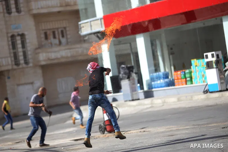 A Palestinian protester throws a molotov cocktail at Israeli security forces during clashes near the Jewish settlement of Bet El, near the West Bank city of Ramallah, on October 13, 2015. A wave of stabbings that hit Isr...