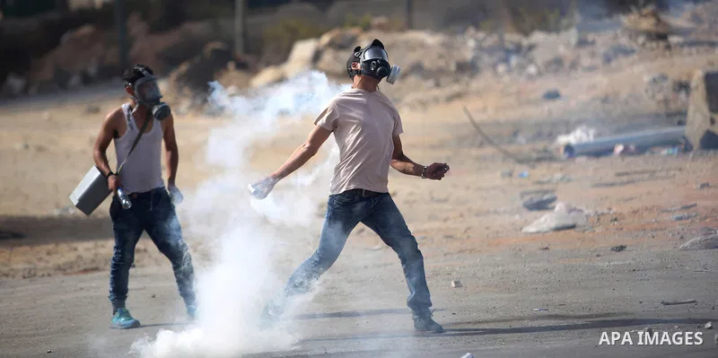 A Palestinian protester throws back a tear gas canister during clashes with Israeli security forces near the Jewish settlement of Bet El, near the West Bank city of Ramallah, on October 13, 2015. A wave of stabbings that...