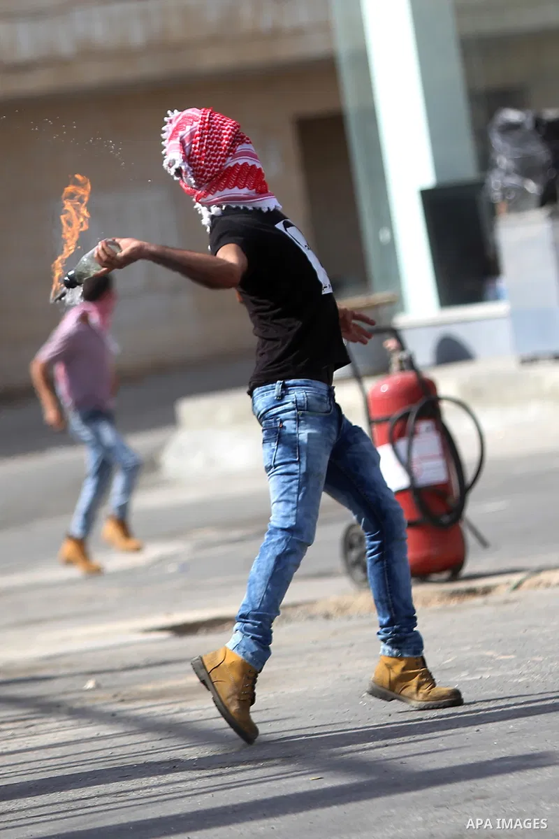 A Palestinian protester throws a molotov cocktail at Israeli security forces during clashes near the Jewish settlement of Bet El, near the West Bank city of Ramallah, on October 13, 2015. A wave of stabbings that hit Isr...