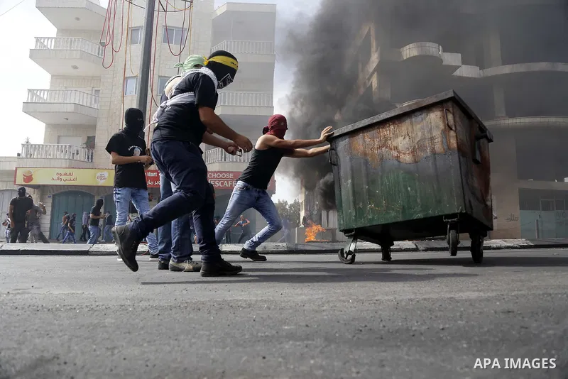 Palestinian protesters take cover during clashes with Israeli security forces in the West Bank city of Bethlehem, on October 13, 2015. A wave of stabbings that hit Israel, Jerusalem and the West Bank this month along wit...