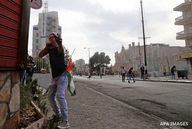 A Palestinian protester uses a sling shot to throw stones at Israeli security forces during clashes in the West Bank city of Bethlehem, on October 13, 2015. A wave of stabbings that hit Israel, Jerusalem and the West Ban...