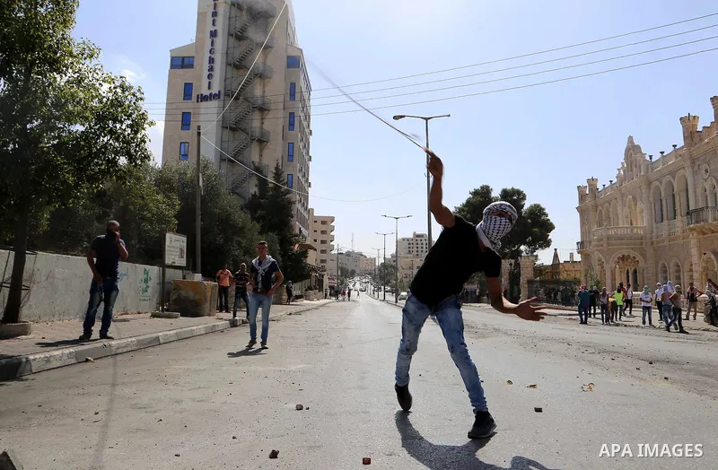 A Palestinian protester uses a sling to throw stones at Israeli troops during clashes in the West Bank city of Bethlehem October 14, 2015. Seven Israelis and 30 Palestinians, including children and assailants, have been...