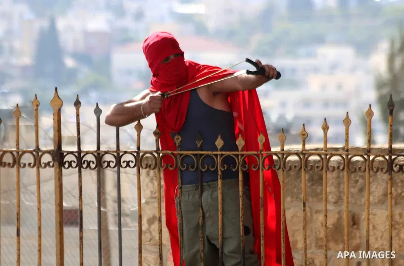 A Palestinian protester uses a sling to throw stones at Israeli troops during clashes in the West Bank city of Bethlehem October 14, 2015. Seven Israelis and 30 Palestinians, including children and assailants, have been...