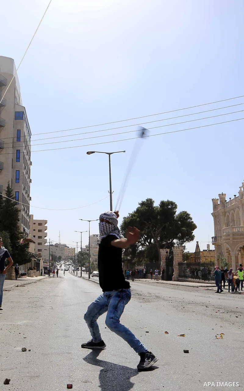 A Palestinian protester uses a sling to throw stones at Israeli troops during clashes in the West Bank city of Bethlehem October 14, 2015. Seven Israelis and 30 Palestinians, including children and assailants, have been...