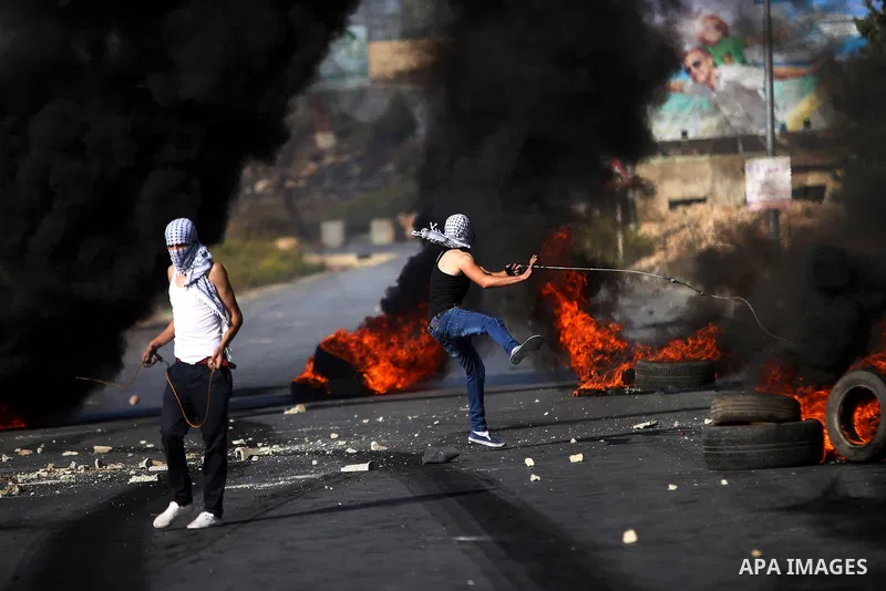 A Palestinian protester uses a sling shot to throw stones at Israeli security forces during clashes near the Jewish settlement of Bet El, near the West Bank city of Ramallah, on October 14, 2015. Seven Israelis and 30 Pa...