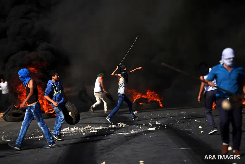 A Palestinian protester uses a sling shot to throw stones at Israeli security forces during clashes near the Jewish settlement of Bet El, near the West Bank city of Ramallah, on October 14, 2015. Seven Israelis and 30 Pa...