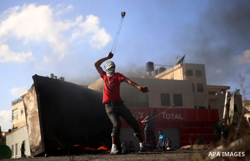 A Palestinian protester uses a sling shot to throw stones at Israeli security forces during clashes near the Jewish settlement of Bet El, near the West Bank city of Ramallah, on October 14, 2015. Seven Israelis and 30 Pa...