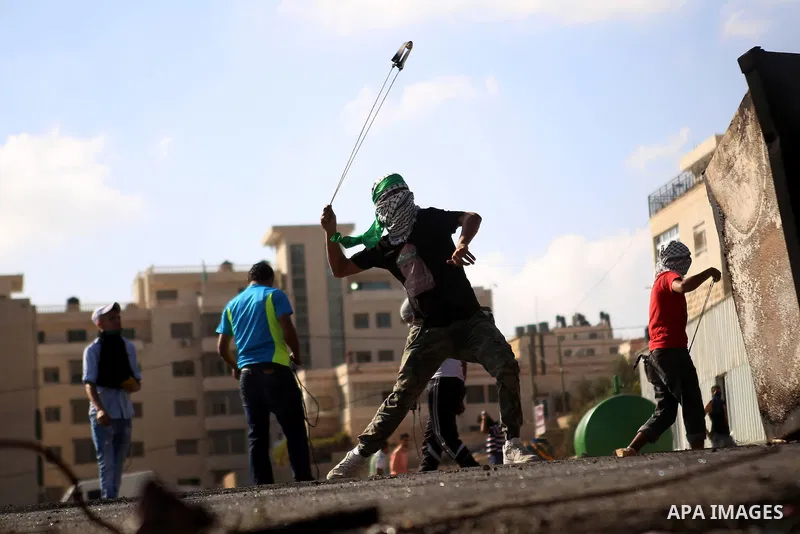 A Palestinian protester uses a sling shot to throw stones at Israeli security forces during clashes near the Jewish settlement of Bet El, near the West Bank city of Ramallah, on October 14, 2015. Seven Israelis and 30 Pa...