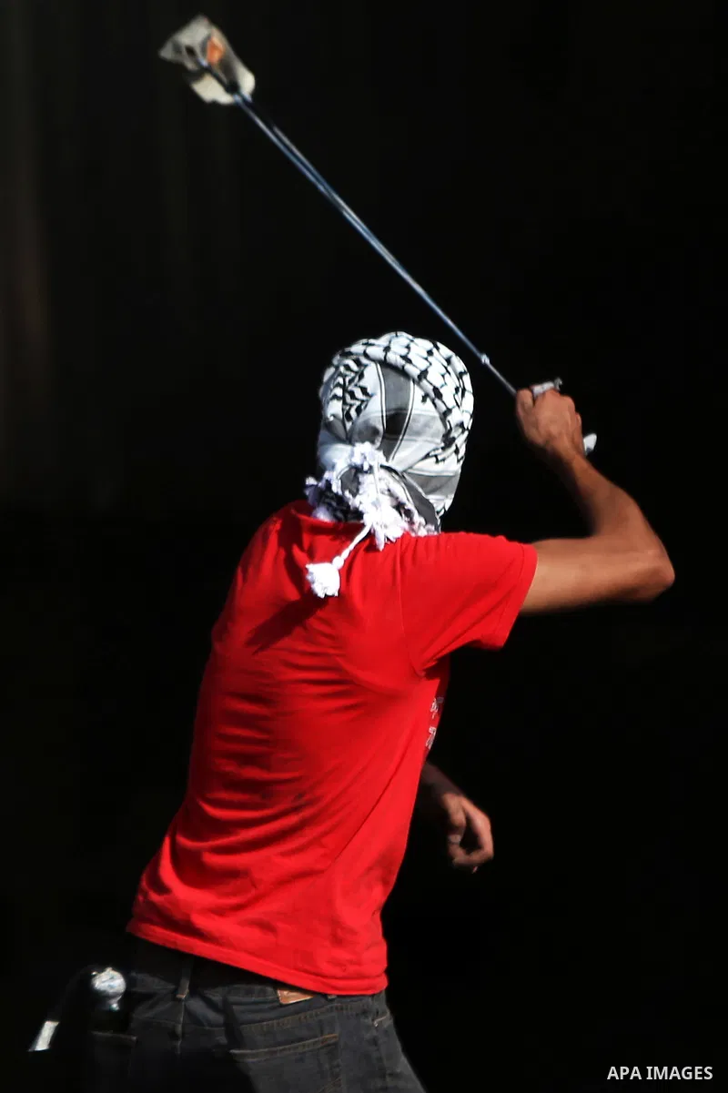A Palestinian protester uses a sling shot to throw stones at Israeli security forces during clashes near the Jewish settlement of Bet El, near the West Bank city of Ramallah, on October 14, 2015. Seven Israelis and 30 Pa...
