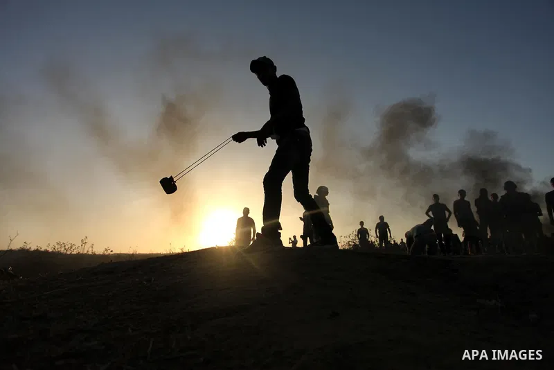 A masked Palestinian protester hurls a stone towards Israeli troops during clashes near a border fence between Israel and the Gaza Strip on October 14, 2015 east of Bureij in central Gaza. The outbreak of violence betwee...