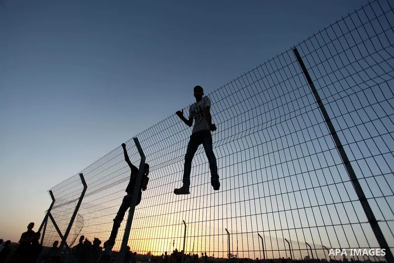 Palestinian protesters climb the border fence during clashes with Israeli troops between Israel and the Gaza Strip on October 14, 2015 east of Bureij in central Gaza. The outbreak of violence between Palestinians and Isr...